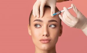 Woman receiving forehead injection during wrinkle treatment, illustrating Xeomin vs. BOTOX options for smoother, youthful skin results.