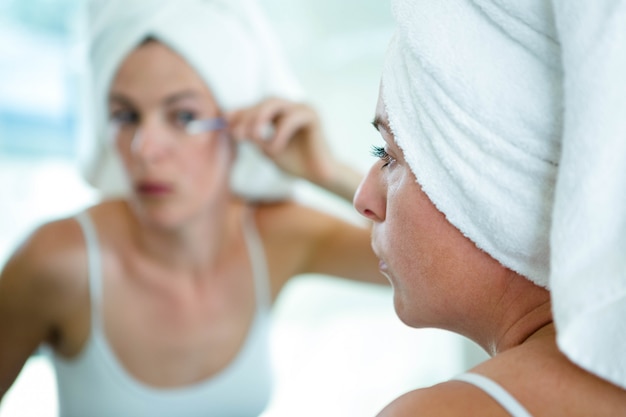 woman-wearing-towel-her-head-applying-mascara_107420-12746